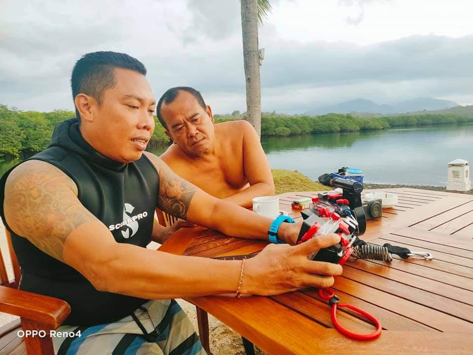 Two men look at an underwater photography setup near Menjangan Island, Bali.