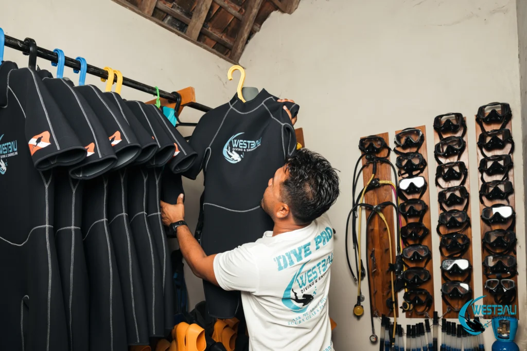 A dive professional hangs a wetsuit in the equipment room at West Bali Diving & Snorkeling.