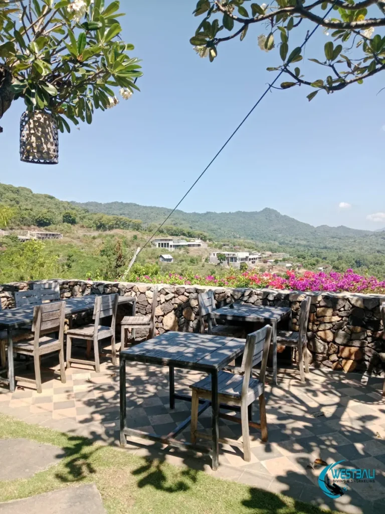 Outdoor dining tables with a hillside view at Senja Restaurant in Sumberkima.